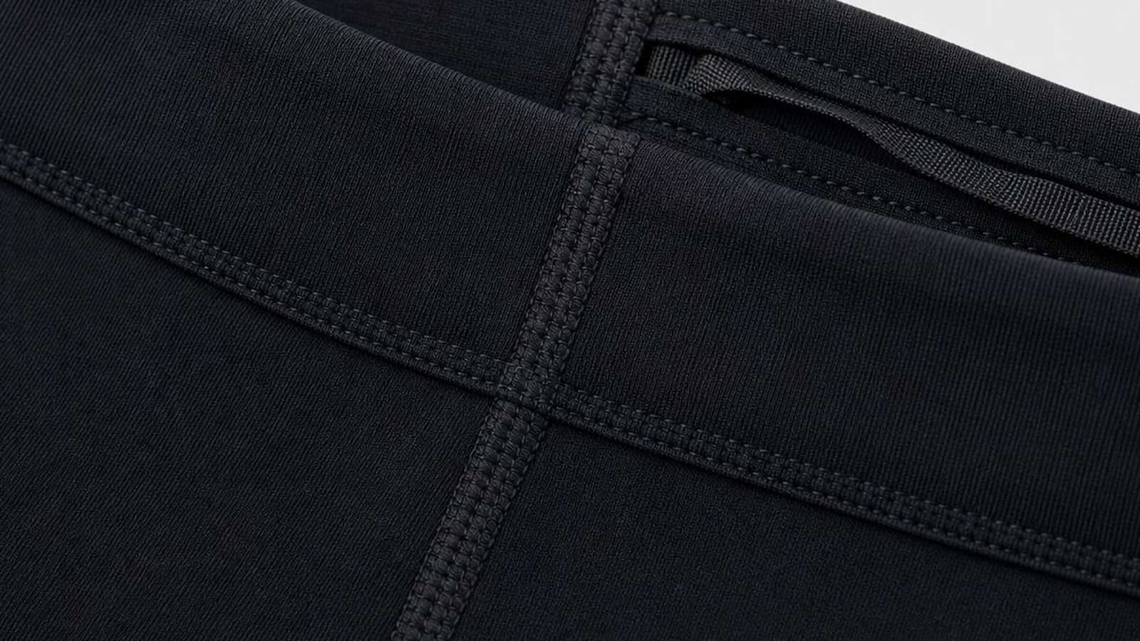 Flatlock seam construction detail on black compression fabric